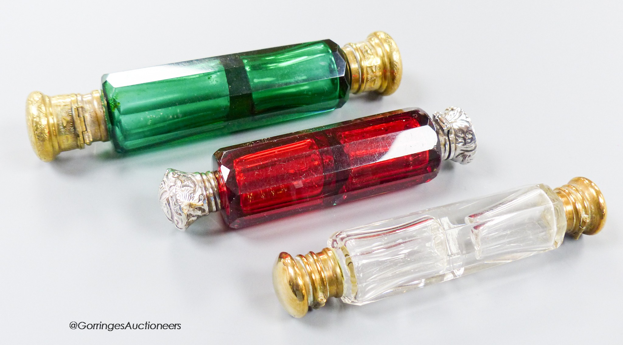 A late 19th century white metal mounted ruby glass decagonal double ended scent bottle, 12cm and two other base metal mounted glass scent bottles.